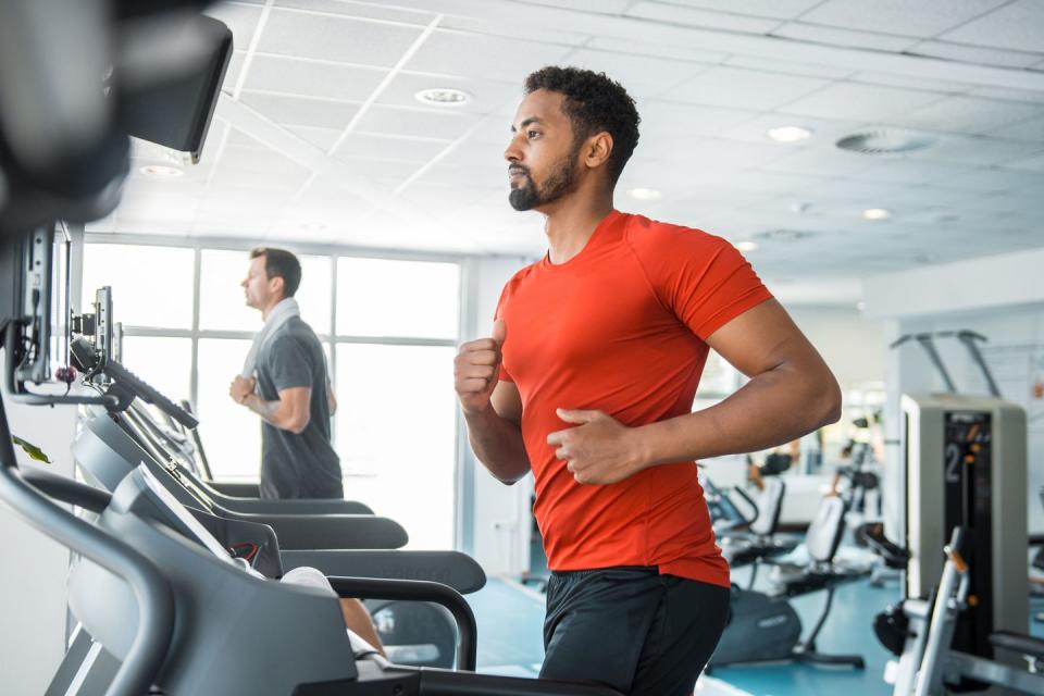 two male friends running on the treadmill in the gym