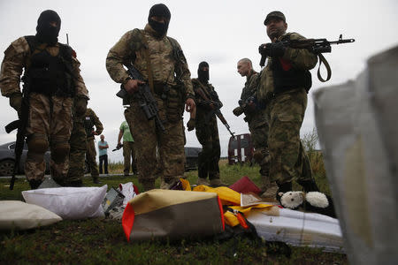 Pro-Russian separatists look at passengers' belongings at the crash site of Malaysia Airlines flight MH17, near the settlement of Grabovo in the Donetsk region, July 18, 2014. REUTERS/Maxim Zmeyev