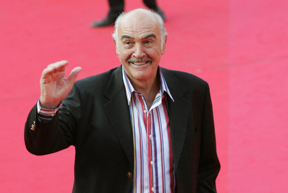 Sir Sean Connery waves to cameras while on a red carpet. 