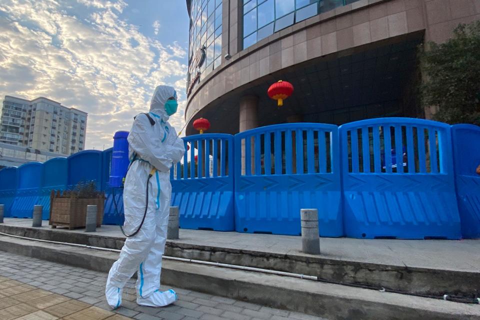 A worker in personal protective equipment carries disinfecting equipment in Wuhan, China,  on Feb. 6, 2021.