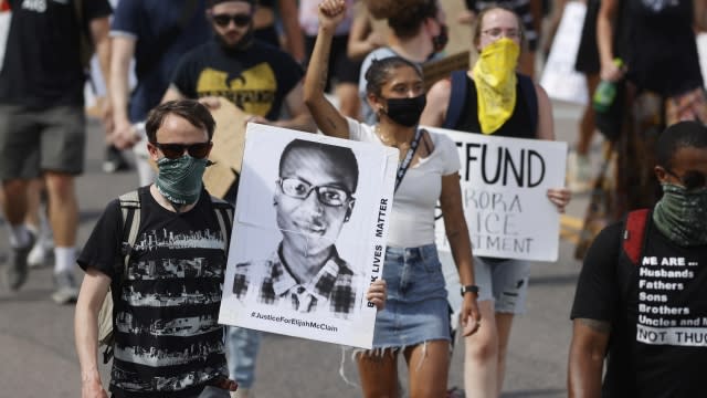 Demonstrators carry placards during a rally and march over the death of Elijah McClain