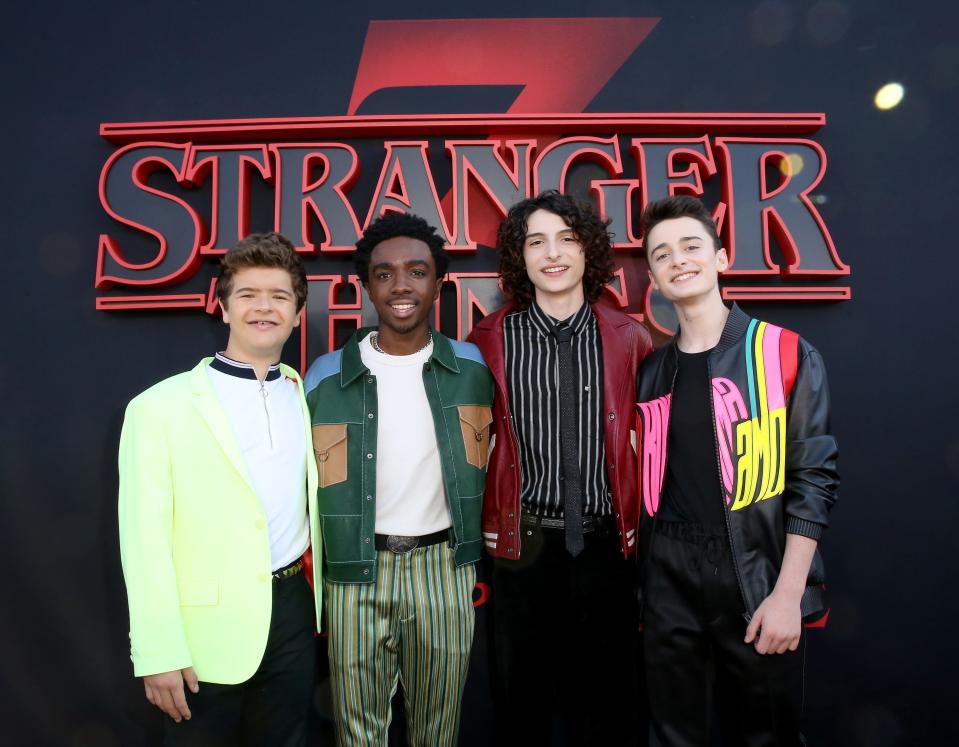 Gaten Matarazzo, Caleb McLaughlin, Noah Schnapp, and Finn Wolfhard standing in front of a Stranger Things logo