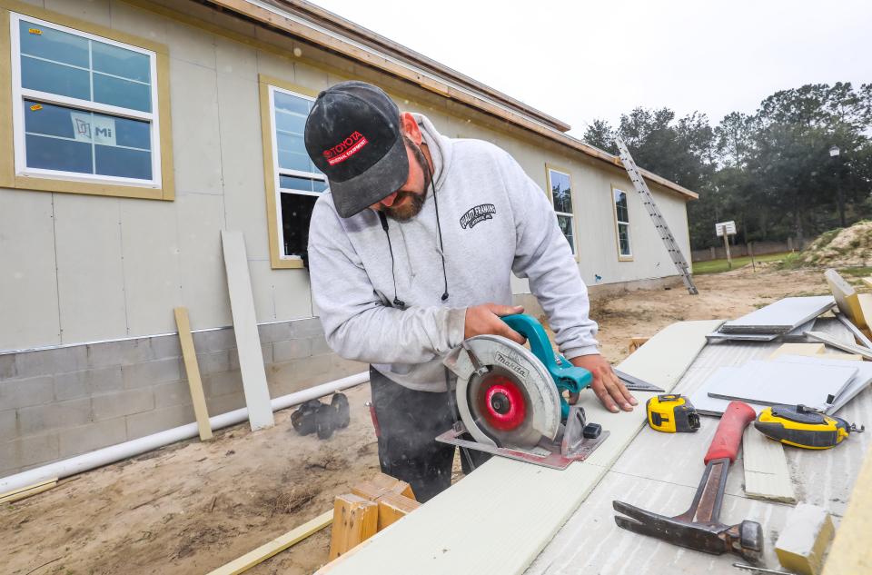 Construction worker Steven Nilsen with Quality Framing, cuts siding for a new home being built in Woodfield Crossings on Dec. 20.