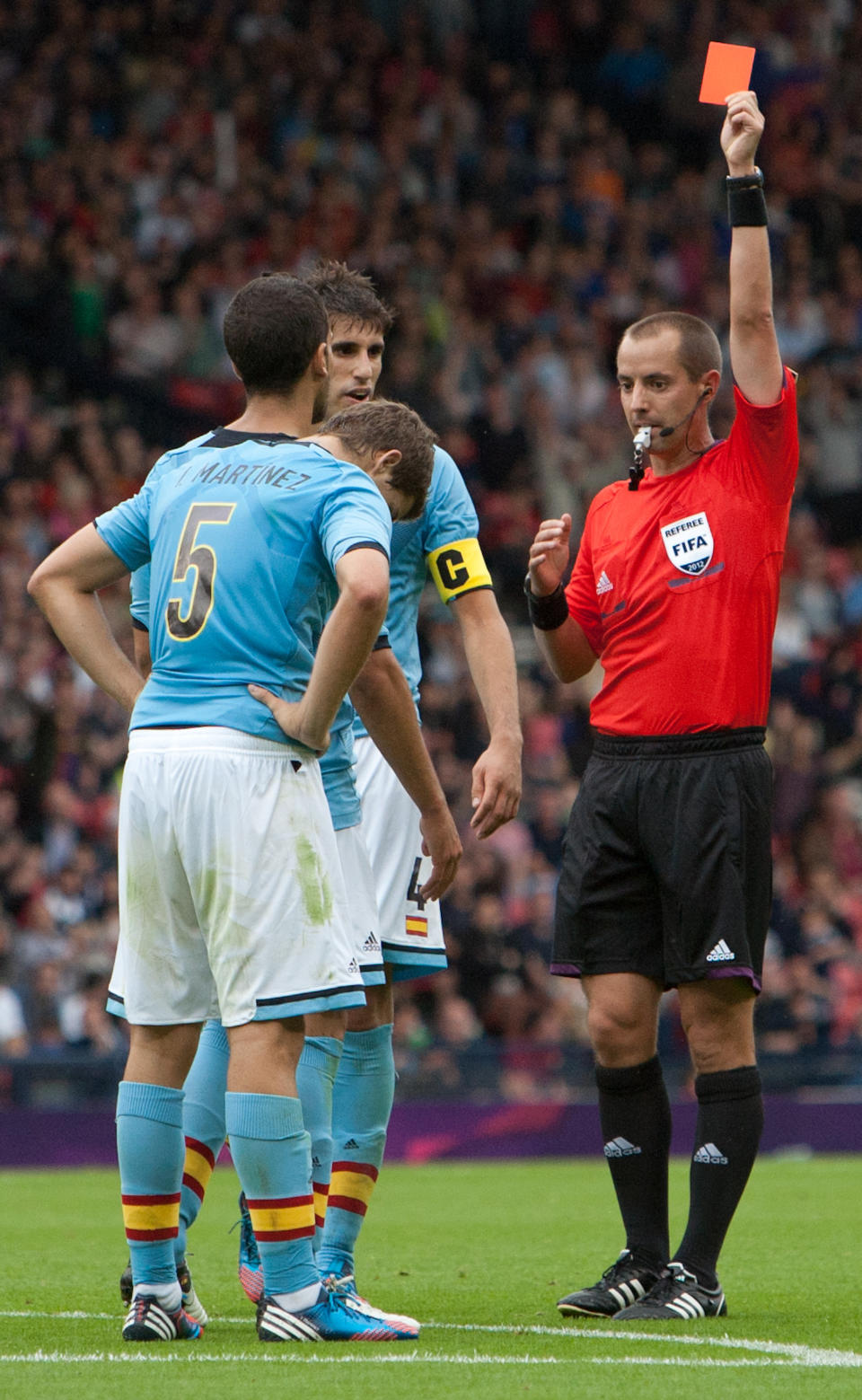 FILE - In this Thursday July 26, 2012 file photo Spain's Inigo Martinez, left, is shown a red card by referee Mark Geiger during the group D men's soccer match between Japan and Spain at the London 2012 Summer Olympics at Hampden Park Stadium in Glasgow, Scotland. Mark Geiger aims to become the first American referee to advance from the group stage in the World Cup in Brazil. (AP Photo/Chris Clark, File)