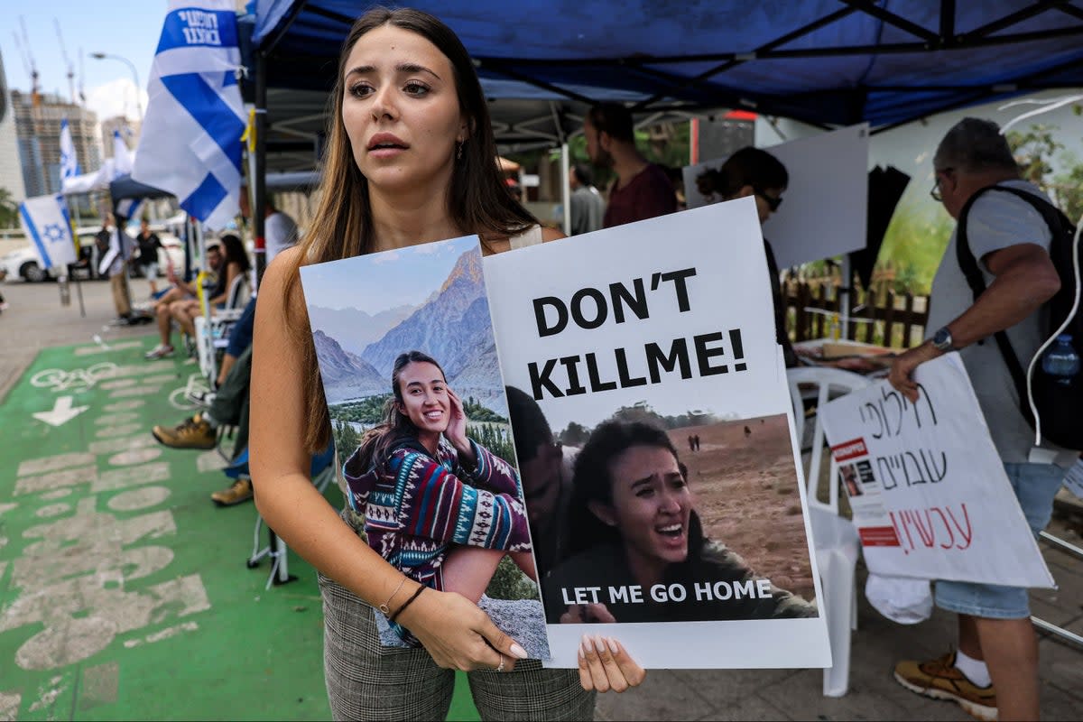 A friend of Israeli student Noa Argamani, one of the Israeli hostages held by Hamas, stands with a sign showing her face (AFP via Getty Images)