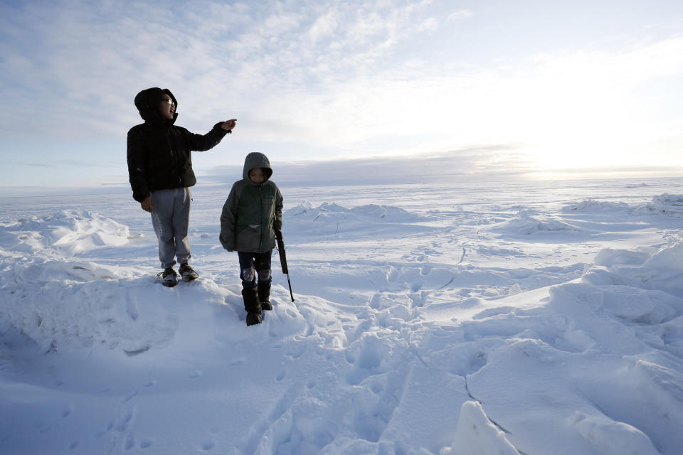 In this Saturday, Jan. 18, 2020, photo, George Chakuchin, left, and Mick Chakuchin look out over the Bering Sea near Toksook Bay, Alaska. The first Americans to be counted in the 2020 Census starting Tuesday, Jan. 21, live in this Bering Sea coastal village. The Census traditionally begins earlier in Alaska than the rest of the nation because frozen ground allows easier access for Census workers, and rural Alaska will scatter with the spring thaw to traditional hunting and fishing grounds. (AP Photo/Gregory Bull)