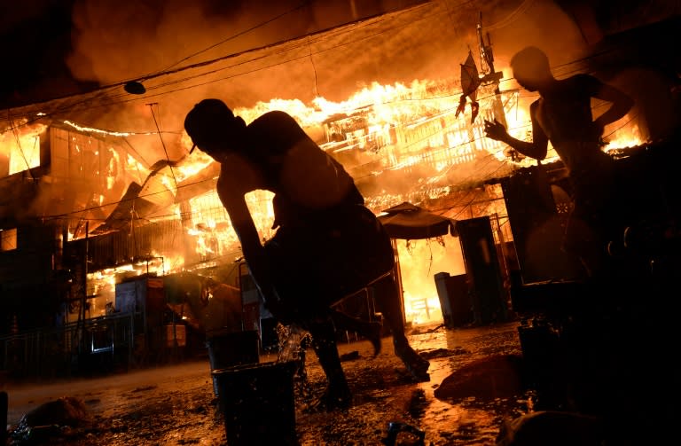 Local residents try to extinguish a huge fire that razed a slum in Manila on January 1, 2016