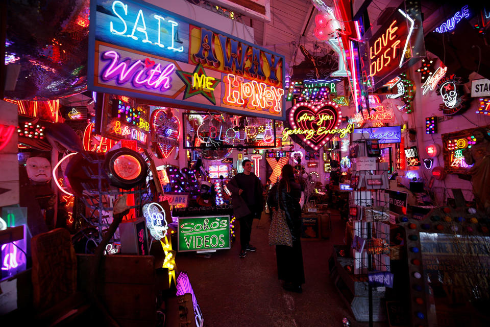 People pose as they take pictures in front of neon lights