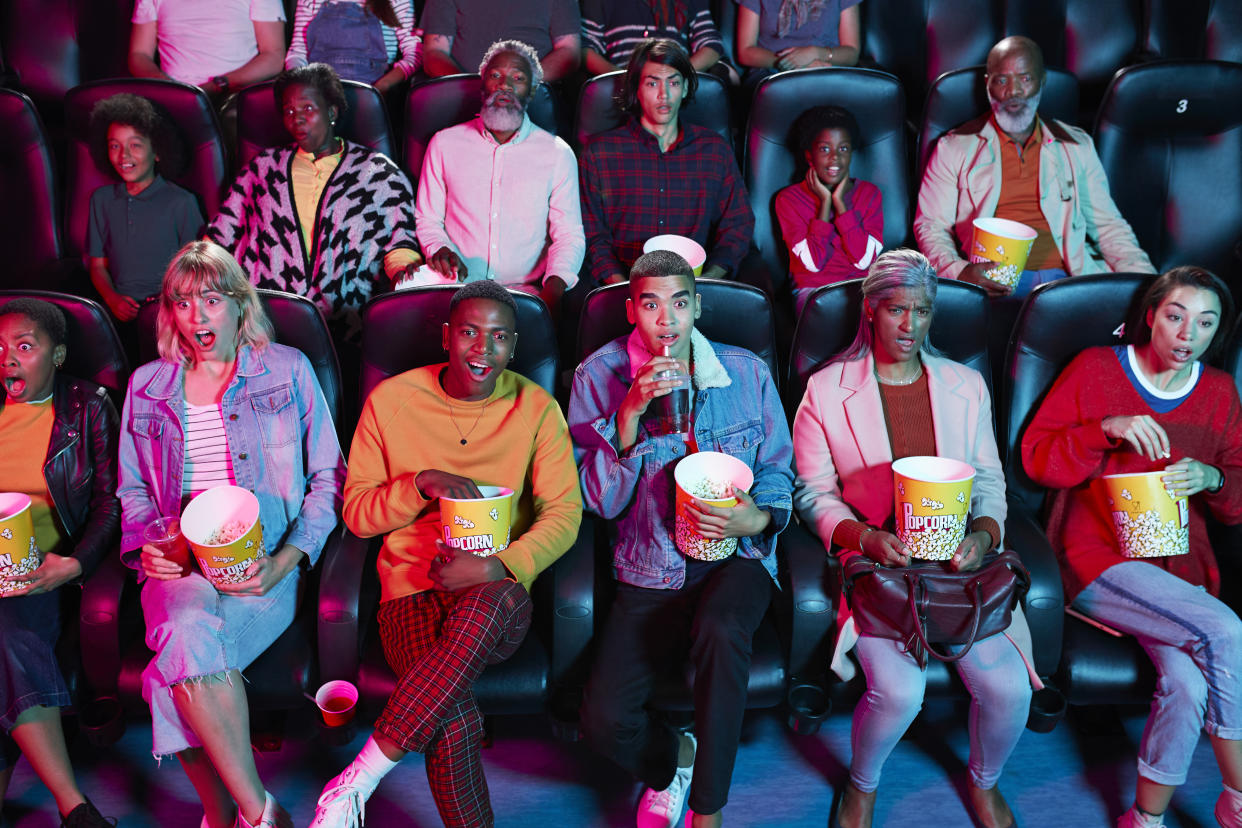 Shocked audience enjoying thriller movie with popcorn at cinema hall