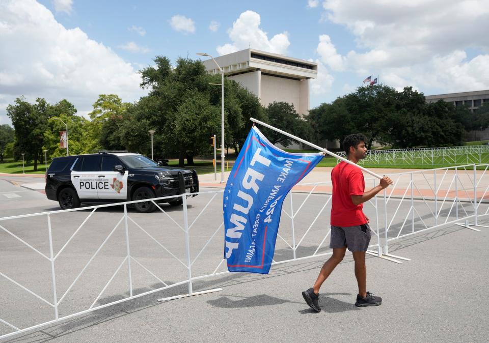 Travis County Republican Party precinct chair Esala Wueschner carries a Trump flag outside the LBJ Presidential Library Monday July 29, 2024, before President Joe Biden spoke at an event there.