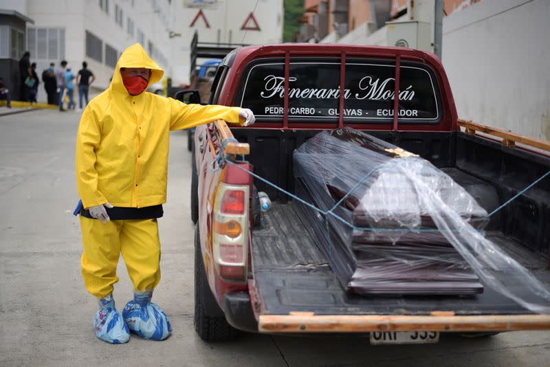 A funeral home worker in a protective suit waits with a coffin on a pick-up truck outside Los Ceibos hospital after Ecuador reported new cases of coronavirus disease (COVID-19), in Guayaquil
