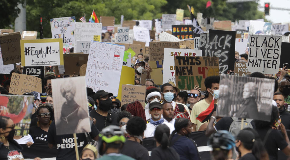 People taking part in a Juneteenth march hold signs as they fill 23rd Ave. in Seattle, Friday, June 19, 2020. Thousands of people marched to honor the Juneteenth holiday and to protest against police violence and racism. (AP Photo/Ted S. Warren)