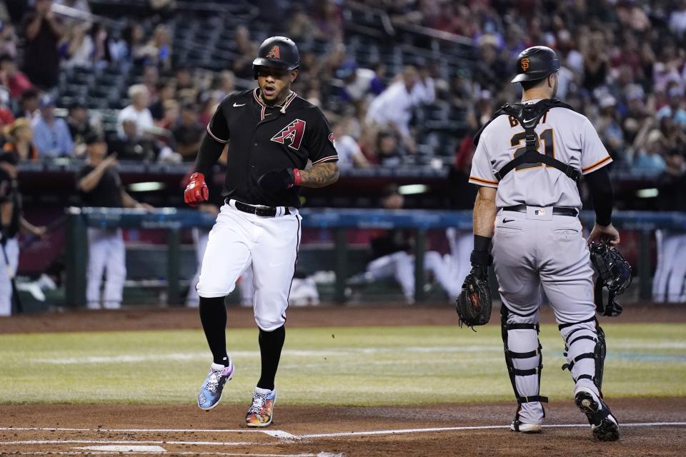 Arizona Diamondbacks' Ketel Marte, left, scores as San Francisco Giants catcher Joey Bart, right, waits for a possible throw during the first inning of a baseball game Wednesday, July 6, 2022, in Phoenix. (AP Photo/Ross D. Franklin)