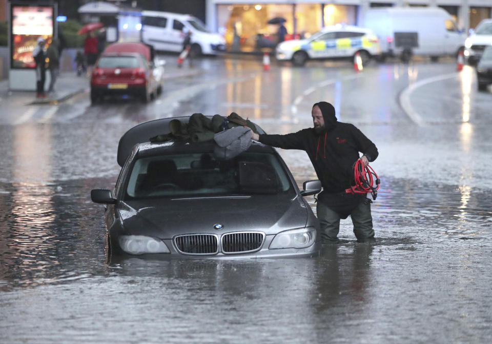 A man gathers items from a car along a flooded street, Thursday, Nov. 7, 2019, in Sheffield, England, after torrential fell rain in the area. (Danny Lawson/PA via AP)