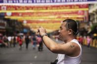 A Chinese tourist with a tattoo of China's late Chairman Mao Zedong takes pictures in Bangkok's Chinatown decorated for the Chinese Lunar New Year February 19, 2015. REUTERS/Damir Sagolj/Files