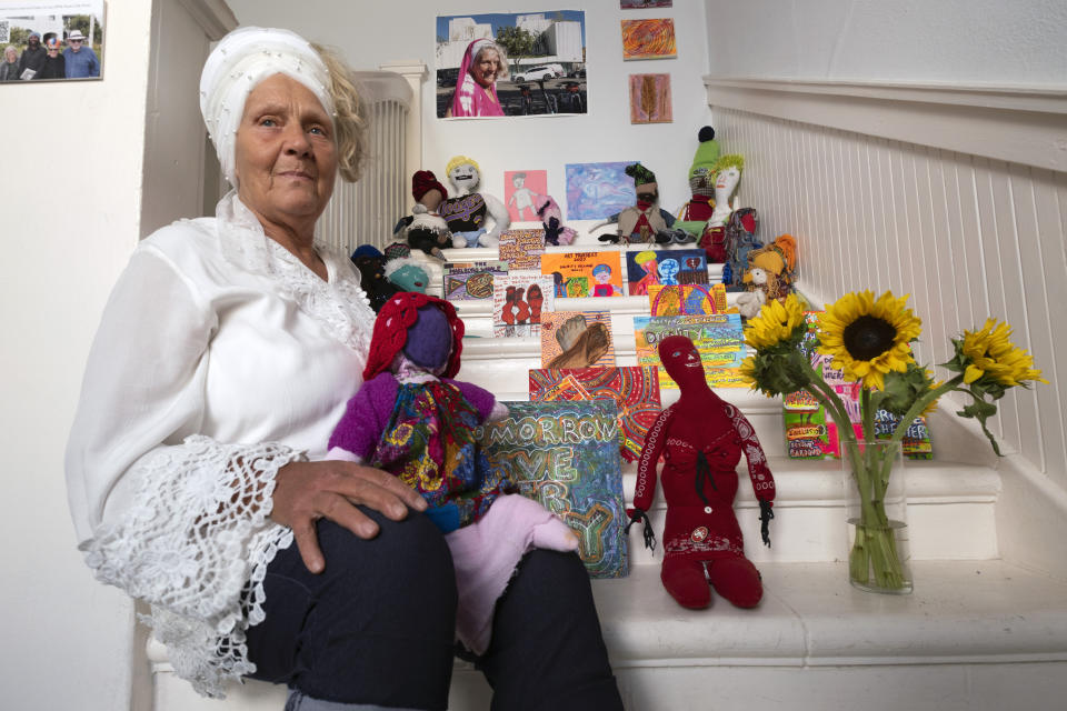 Artist Sumaya Evans sits with her installation "dignity dolls." part of an exhibit titled "Where Has All The (affordable) Housing Gone?" at the Beyond Baroque gallery, Friday, Nov. 3, 2023, in the Venice Beach area of Los Angeles. Evans, who was homeless in Venice for years before recently finding housing, said creating art gave her a sense of self-worth when she was living on the streets. "You get used to being ignored as a homeless woman. People are blind to you when you're outside," she said. "And so being a part of a project like this, being a part of a community, is just so healing." (AP Photo/Richard Vogel)