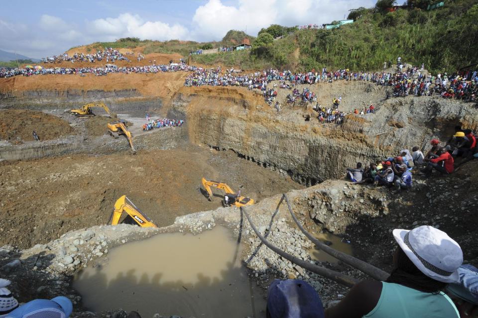 People watch machinery used to dig in search or survivors at a collapsed illegal gold mine in Santander de Quilichao, southern Colombia, Thursday, May 1, 2014. The bodies of three miners have been recovered and an unknown number remain missing, said Temistocles Ortega, governor of the Cauca state. (AP Photo/Oswaldo Paez, El Pais)