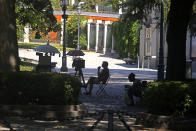 A portrait photographer waits for customers in the Paseo del Prado boulevard in Madrid, Spain, Friday, July 23, 2021. Madrid's tree-lined Paseo del Prado boulevard and the adjoining Retiro park have been added to UNESCO's World Heritage list. The UNESCO World Heritage Committee backed the candidacy that highlighted the green area's introduction of nature into Spain's capital. (AP Photo/Paul White)