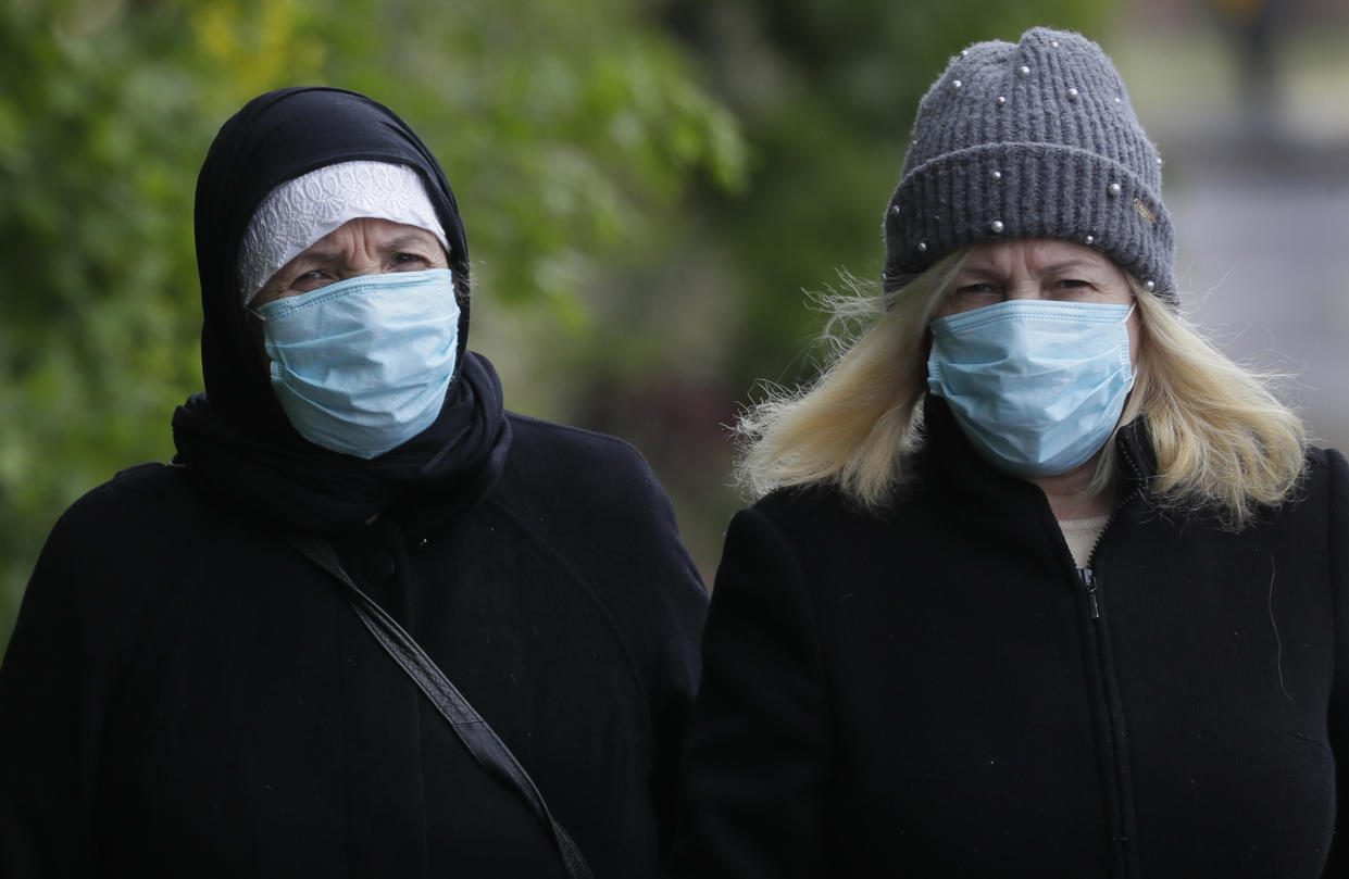 People wear face masks to protect against the coronavirus as they walk in London, Wednesday, April 29, 2020. The Scottish Government is recommending the use of masks in shops and public transport, and Mayor of London Sadiq Khan has called for people to wear facemasks, while the British government does not recommend the face covering.(AP Photo/Kirsty Wigglesworth)