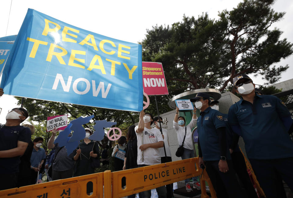 Protesters wearing face masks hold banners as police officers stand guard during a rally to demand the peace on the Korean peninsula and to stop sanctions against North Korea in front of Foreign Ministry before U.S. Deputy Secretary of State Stephen Biegun's arrival to meet with South Korean officials in Seoul, South Korea, Wednesday, July 8, 2020. Biegun arrived on Tuesday in the country on the first leg of his two-stop Asia trip and will meet officials in South Korea and Japan. (AP Photo/Lee Jin-man)