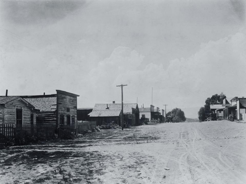 black and white photo of Bannack, Montana, with an open road a few buildings on the left