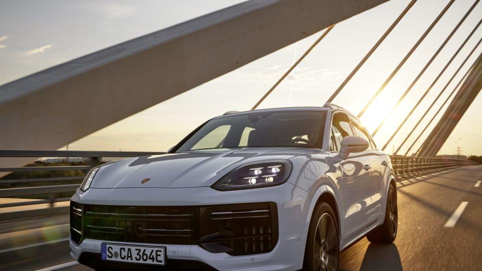 2024 porsche cayenne turbo e hybrid driving over a bridge at dusk