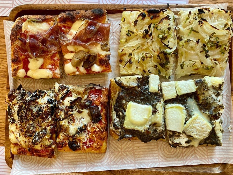 Focaccia choices at La Fabbrica Italiana in Dubai, featuring toppings such as black truffle, onions, San Marzano tomatoes, eggplant, salami, and zucchini.