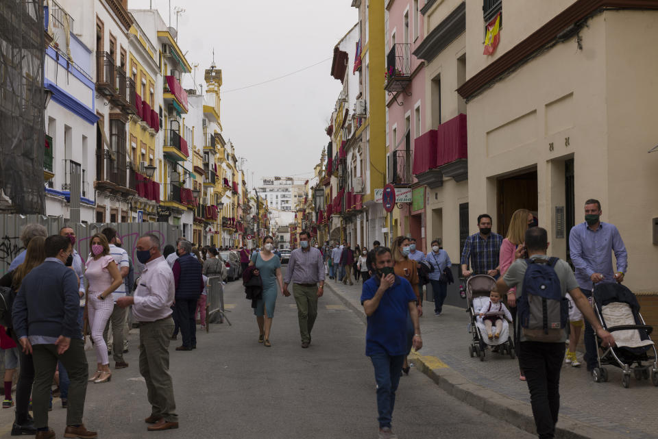 Pedestrians walk past La Esperanza de Triana during the Holy Week in Seville, southern Spain, Tuesday, March 30, 2021. Few Catholics in devout southern Spain would have imagined an April without the pomp and ceremony of Holy Week processions. With the coronavirus pandemic unremitting, they will miss them for a second year. (AP Photo/Laura Leon)