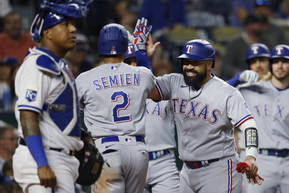 Texas Rangers' Marcus Semien (2) is congratulated by Sandy Leon, right, after hitting a three-run home run as Kansas City Royals catcher Salvador Perez, left, stands at home plate during the sixth inning of a baseball game in Kansas City, Mo., Tuesday, April 18, 2023. (AP Photo/Colin E. Braley)