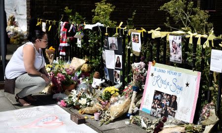 A woman looks at flowers, tributes and messages left for the victims of the fire at the Grenfell apartment tower in North Kensington, London, Britain, June 23, 2017. REUTERS/Hannah McKay