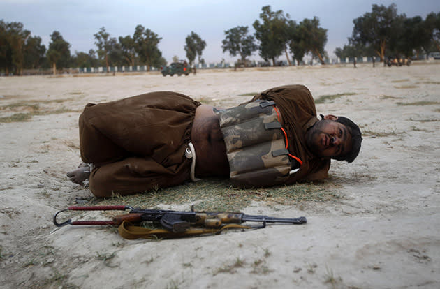 A suicide bomber lies on the ground, his hands tied behind his back, after a bomb expert defused his explosive vest. (Parwiz/Reuters)