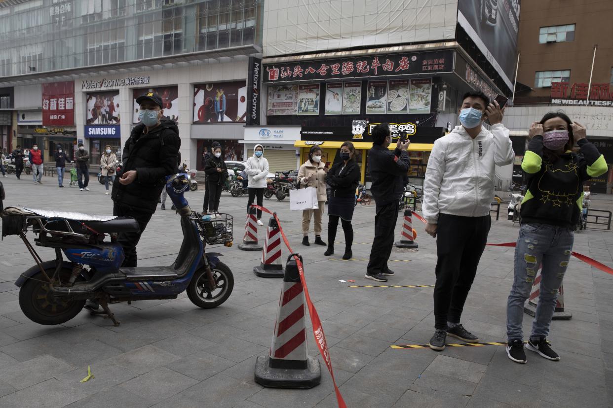 Residents wearing masks to protect against the spread of the coronavirus line up to enter a supermarket in Wuhan in central China's Hubei province on Friday, April 3, 2020. Chinese leaders are trying to revive the economy, but local officials under orders to prevent new infections are enforcing disease checks and other controls that add to financial losses and aggravation for millions of workers.