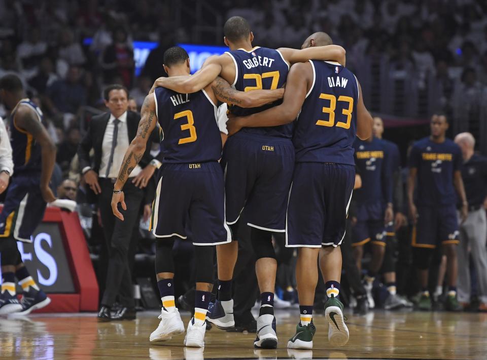 Jazz center Rudy Gobert, center, is helped off the court by center Boris Diaw, right, and guard George Hill, left, on Saturday. (AP)