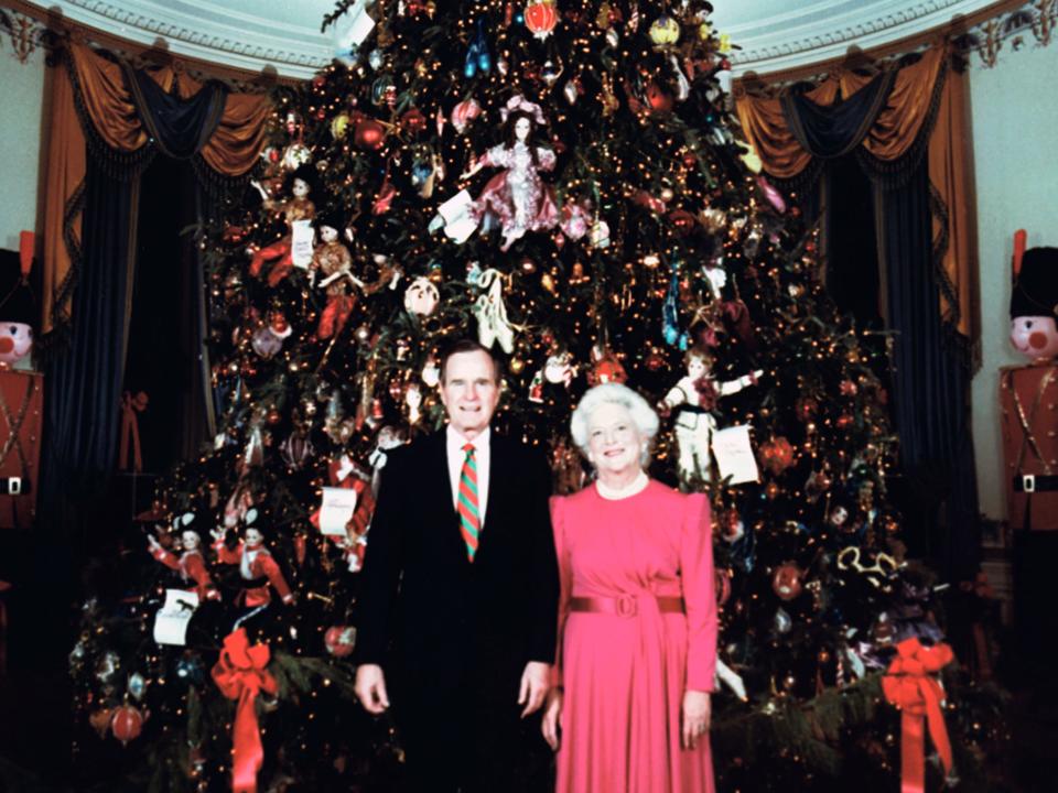 George H.W. Bush and Barbara Bush pose in front of a Christmas tree at the White House.