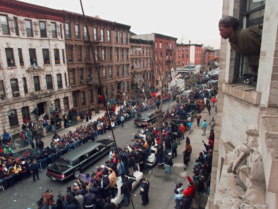 FILE - In this March 18, 1997 file photo, a man looks out his apartment window at the funeral procession for slain rapper Christopher Wallace, known as Notorious B.I.G., in the Brooklyn borough of New York. Considered one of the greatest rappers of all time, Biggie was shot to death on a Los Angeles street in a drive-by on March 9, 1997. (AP Photo/Mark Lennihan, File)