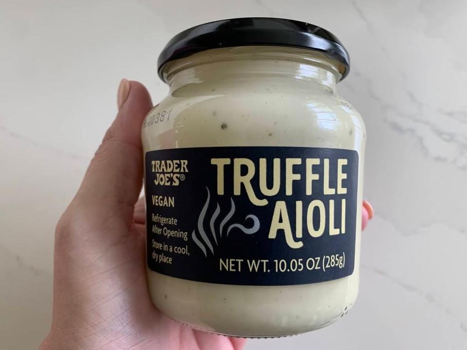 A jar of Trader Joe's truffle aoili on a marble countertop.