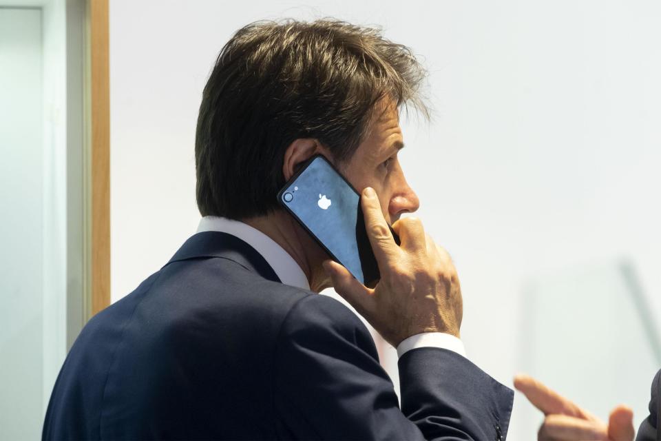 Italy's Prime Minister, Giuseppe Conte, talks at the phone inside a mobile phones shop in the center of Rome, Tuesday, Aug. 27, 2019. While Italians don't know if they'll soon have a new government, let alone who would lead it, U.S. President Donald Trump has cast his vote -- for caretaker Premier Giuseppe Conte. A day after the two finished attending the G-7 summit in France, Trump tweeted on Tuesday that he hoped Conte would "remain" as premier. (Massimo Percossi/ANSA via AP)