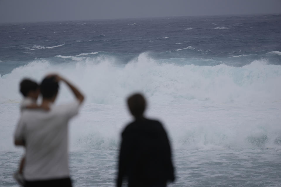 Varias personas de una misma familia observan el oleaje provocado por la cercanía del tifón Mawar en Itoman, en el sur de Japón, el 31 de mayo de 2023. (AP Foto/Hiro Komae)