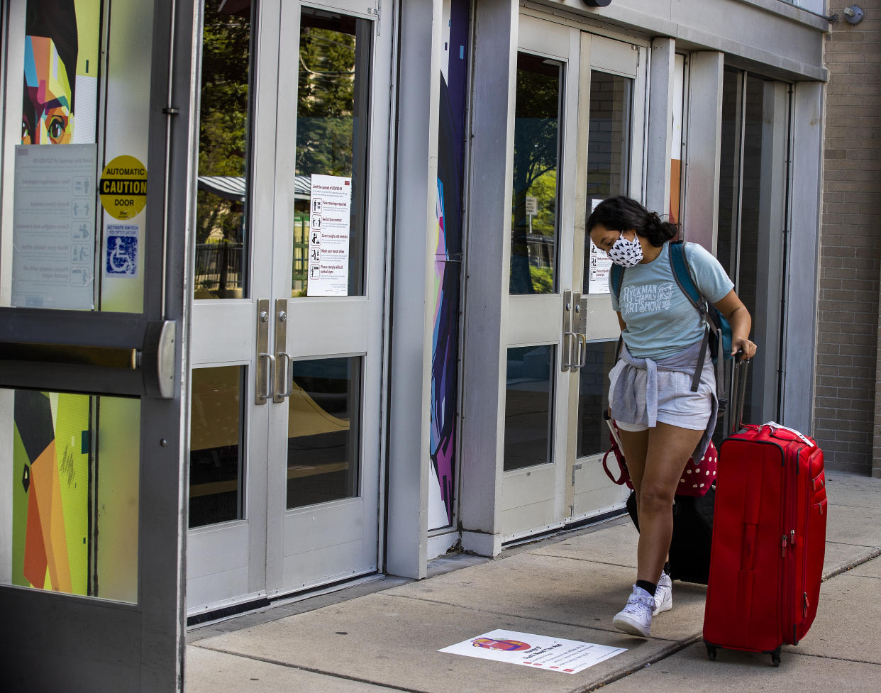 BOSTON - AUGUST 6: A Boston University student moves into the Warren Towers dorm buildings while reading a sign about food apps and coronavirus protocols along Commonwealth Avenue in Boston on Aug. 18, 2020. Recent studies have shown a spike in depression amongst college students because of the coronavirus. (Photo by Stan Grossfeld/The Boston Globe via Getty Images)