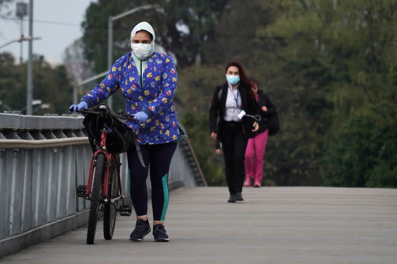 Foto de archivo. Personas usando tapabocas durante el aislamiento preventivo obligatorio decretado por el gobierno para frenar la expansión del coronavirus caminan sobre un puente peatonal en Bogotá