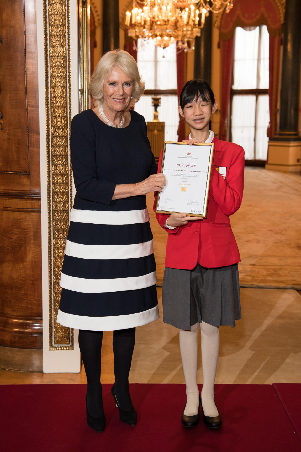 Camilla, Duchess of Cornwall, Vice Patron of The Royal Commonwealth Society, on behalf of Her Majesty The Queen, Patron of The Royal Commonwealth Society, with Janine Shum, Junior Winner, during a reception for winners of The Queen’s Commonwealth Essay Competition at Buckingham Palace on 22 November 2018 in London. (Photo: Jeff Spicer/Getty Images)