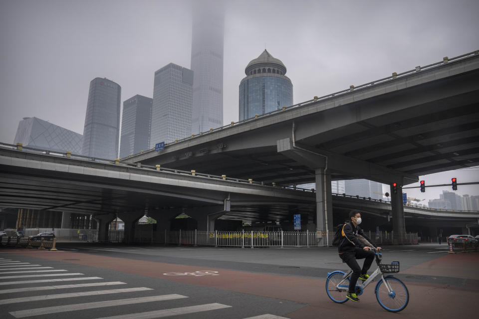 A person wearing a face mask rides across an intersection in the central business district in Beijing during what is normally the morning rush hour, as most nonessential workers in the district have been ordered to work from home, Tuesday, May 10, 2022. China's capital began another round of three days of mass testing for millions of its residents Tuesday in a bid to prevent an outbreak from growing to Shanghai proportions. (AP Photo/Mark Schiefelbein)