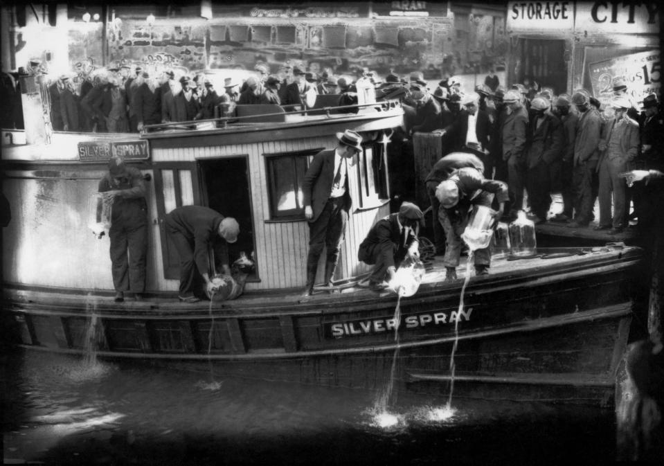 FILE - In this 1922 file photo spectators gather by the side of captured rum runner, Silver Spray, as they watch prohibition agents pour "white lightning" from the five-gallon bottles on the deck into the Elizabeth River, Norfolk, Va. The Prohibition Era, which lasted from Jan. 17, 1920, until December 1933, is now viewed as a failed experiment that glamorized illegal drinking. (Charles S. Borjes/The Virginian-Pilot via AP)
