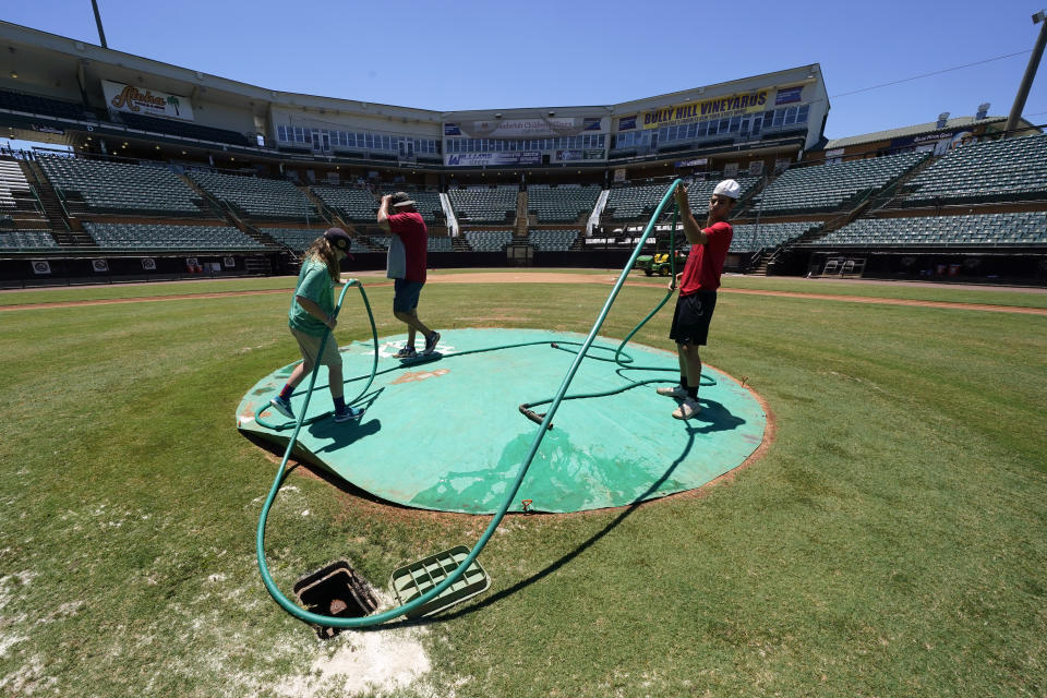 The grounds crew prepares The Ballpark at Jackson before a home game for the Winnipeg Goldeyes of the American Association, Tuesday, June 22, 2021, in Jackson, Tenn. When Major League Baseball stripped 40 teams of their affiliation in a drastic shakeup of the minor leagues this winter, Jackson lost the Jackson Generals, the Double-A affiliate of the Arizona Diamondbacks. The Goldeyes are playing their home games in Jackson due to COVID-19 restrictions. (AP Photo/Mark Humphrey)