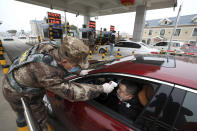 A militia member uses a digital thermometer to take a driver's temperature at a checkpoint at a highway toll gate in Wuhan in central China's Hubei Province, Thursday, Jan. 23, 2020. China closed off a city of more than 11 million people Thursday in an unprecedented effort to try to contain a deadly new viral illness that has sickened hundreds and spread to other cities and countries amid the Lunar New Year travel rush. (Chinatopix via AP)