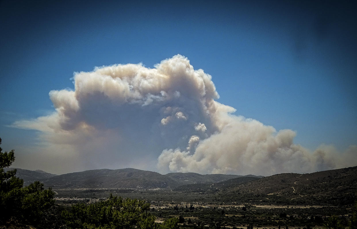 A cloud of smoke from a forest fire rises over the island of Rhodes, Greece, Saturday, July 22, 2023. A large wildfire burning on the Greek island of Rhodes for a fifth day has forced authorities to order an evacuation of four locations, including two seaside resorts. (Argyris Mantikos/Eurokinissi via AP)