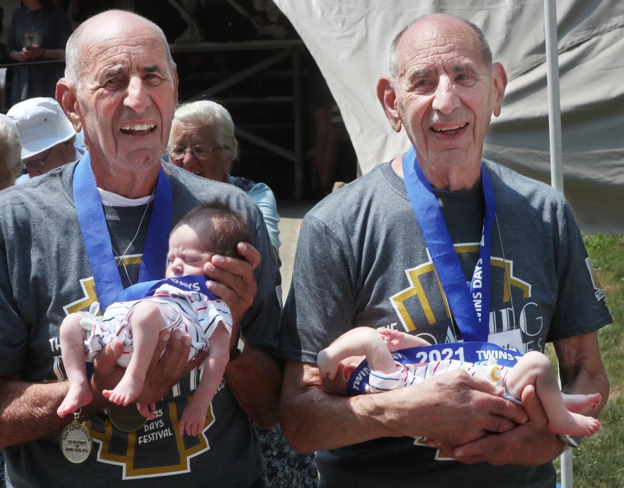 The oldest twins Selig and Irwin Lurie, 90, hold the youngest twins, 11 days old, Ryan and Owen Dean, from Medina, at the 46th Annual Twins Day Festival on Saturday Aug. 7, 2021 in Twinsburg.