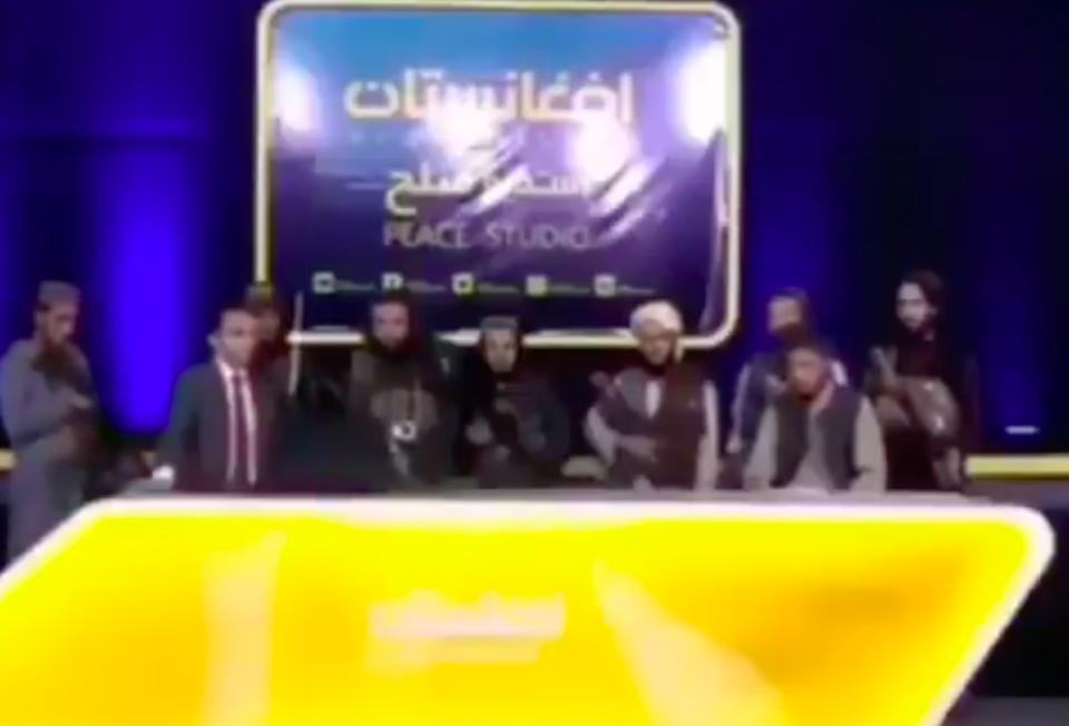 A number of armed Taliban fighters flank the news anchor. (Peace Studio/Twitter)