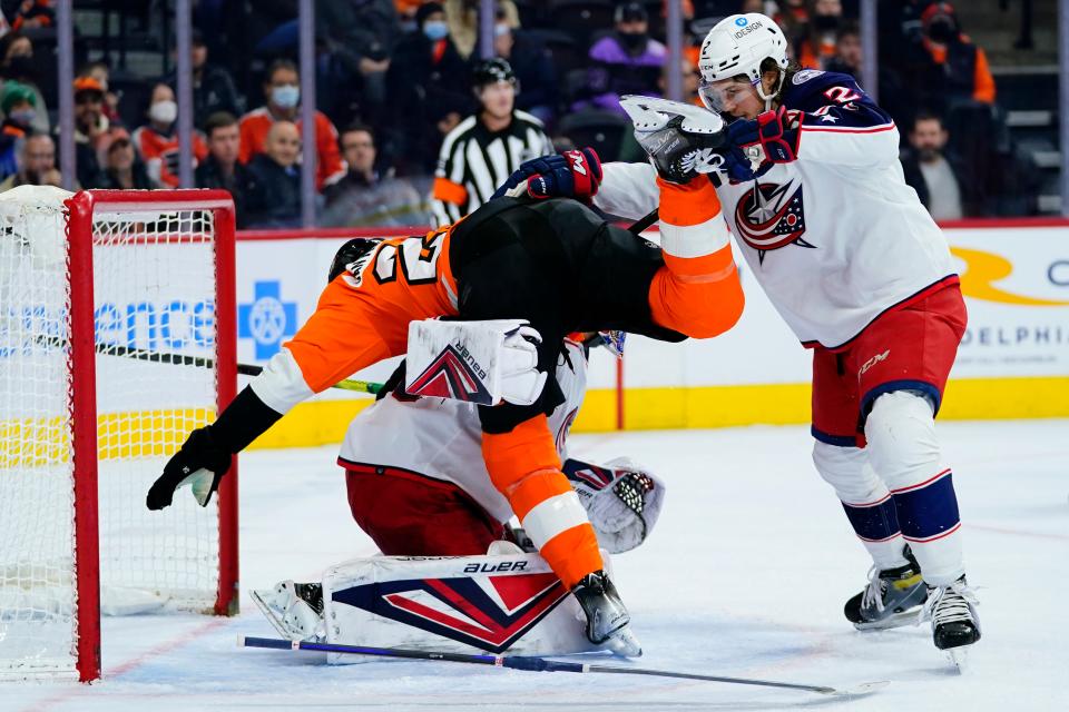 Philadelphia Flyers' James van Riemsdyk, center, collides with Columbus Blue Jackets' Elvis Merzlikins, left, and Andrew Peeke during the second period of an NHL hockey game, Thursday, Jan. 20, 2022, in Philadelphia. (AP Photo/Matt Slocum)