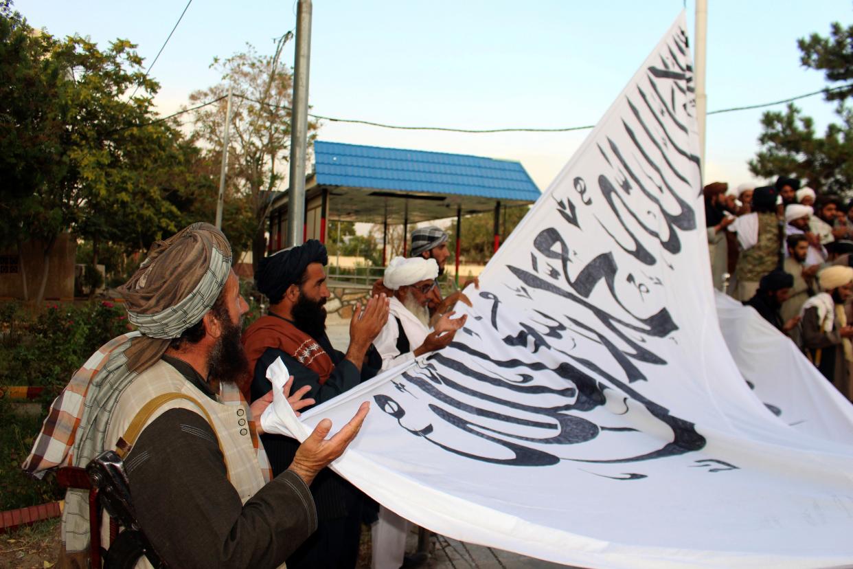 Taliban fighters pray while raising their flag at the Ghazni provincial governor's house in Ghazni, southeastern, Afghanistan, Sunday, Aug. 15, 2021.